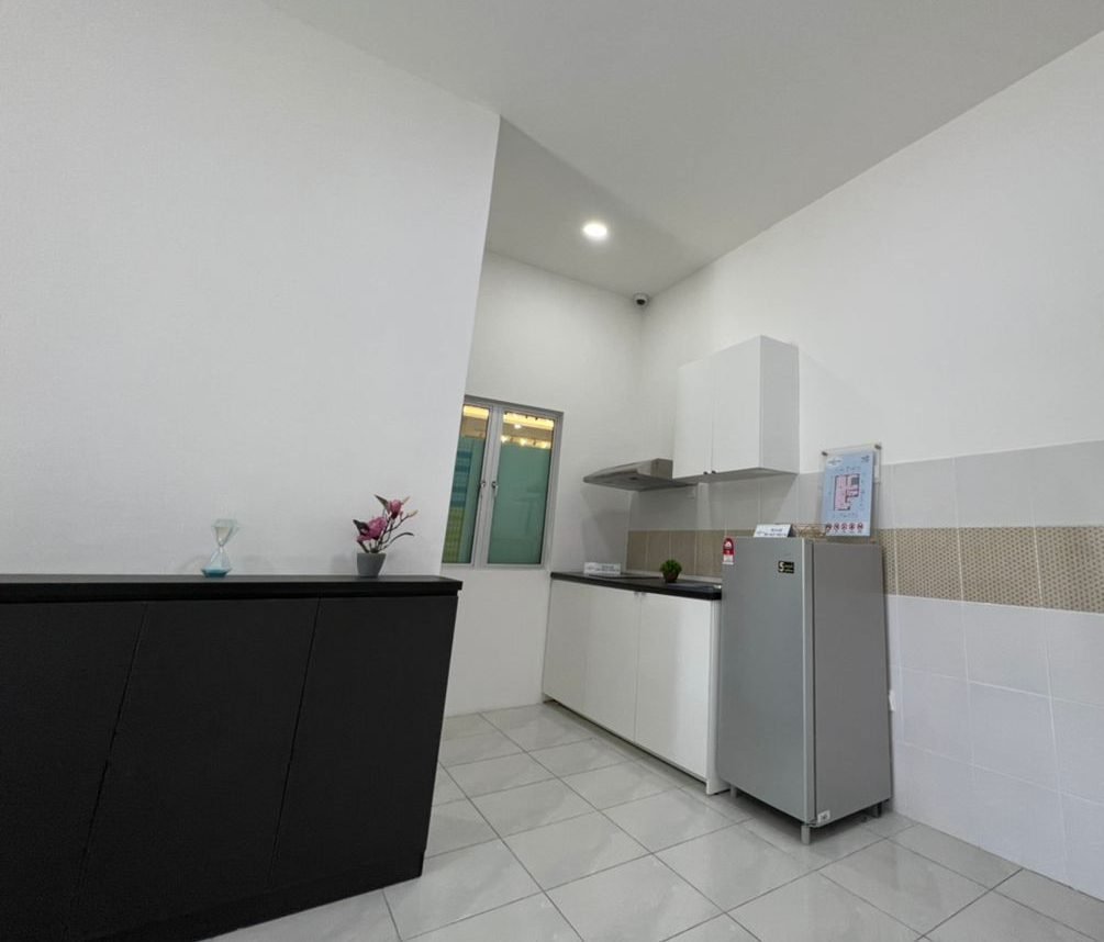 Kitchen with fitted cabinets and refrigerator in the 1-bedroom show unit