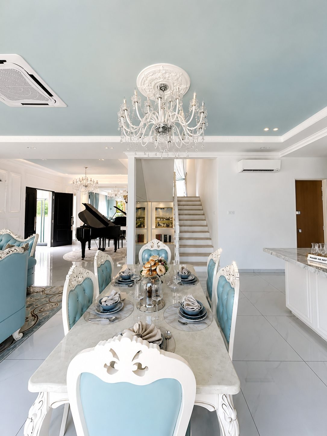 Dining table under a chandelier, with the living hall behind, Thompson Prestige